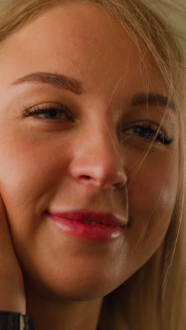 Pretty positive blonde woman smiles to beloved man stroking lady cheek by palm on light background in spacious room close view slow motion