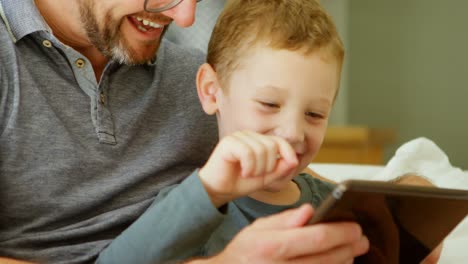 Father-and-son-using-digital-tablet-on-sofa-at-home-4k