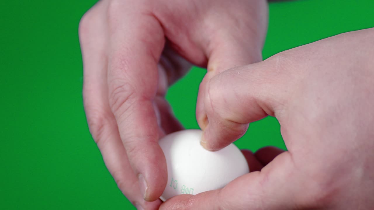 Men's hands with a knife break raw egg.