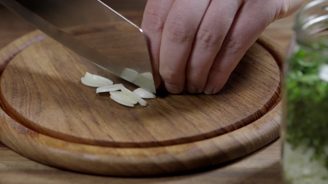 Chef slicing fresh garlic on wooden board
