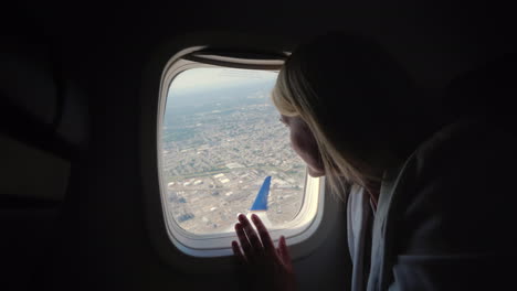 una pasajera mira por la ventana del avión al suelo debajo de donde se encuentra la gran metrópolis