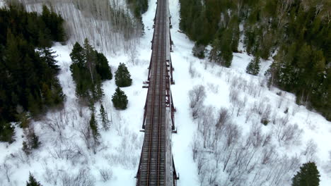 Drohnenflug-über-Eine-Eisenbahnbrücke-Im-Winter-Mit-Schnee-Auf-Dem-Boden