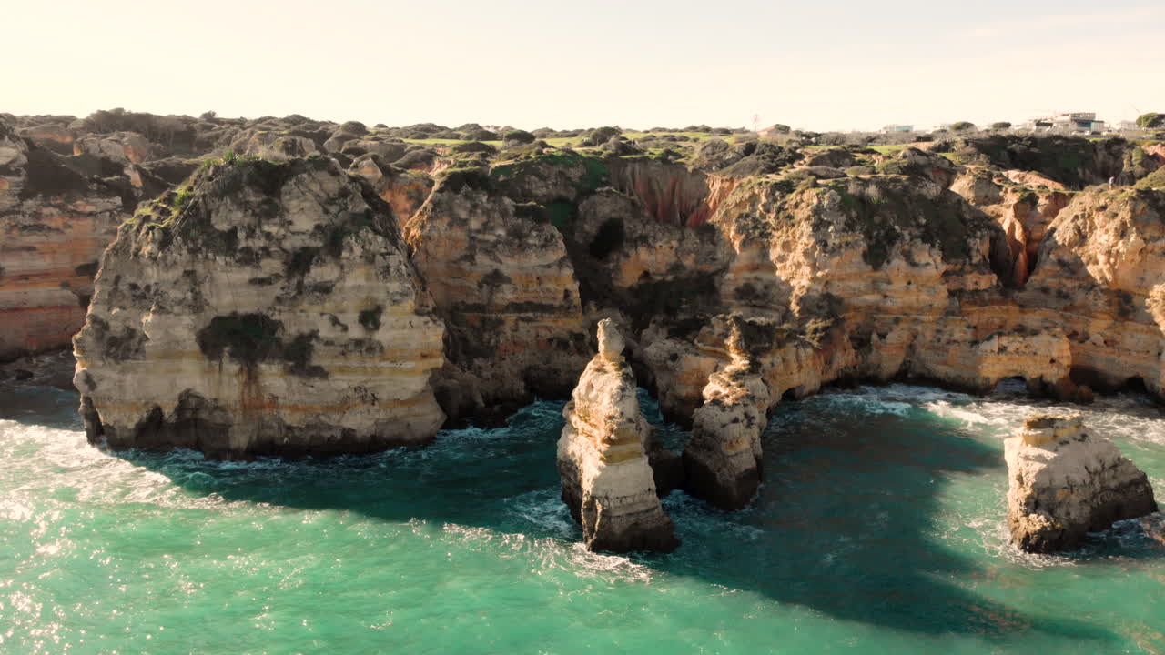 AÉREA: Acantilados y rocas en Portugal desde un lateral con agua azul moviéndose alrededor