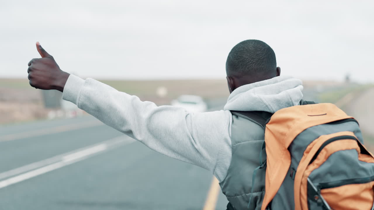 Man hitchhiking on a road with a backpack