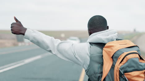 man hitchhiking on a road with a backpack