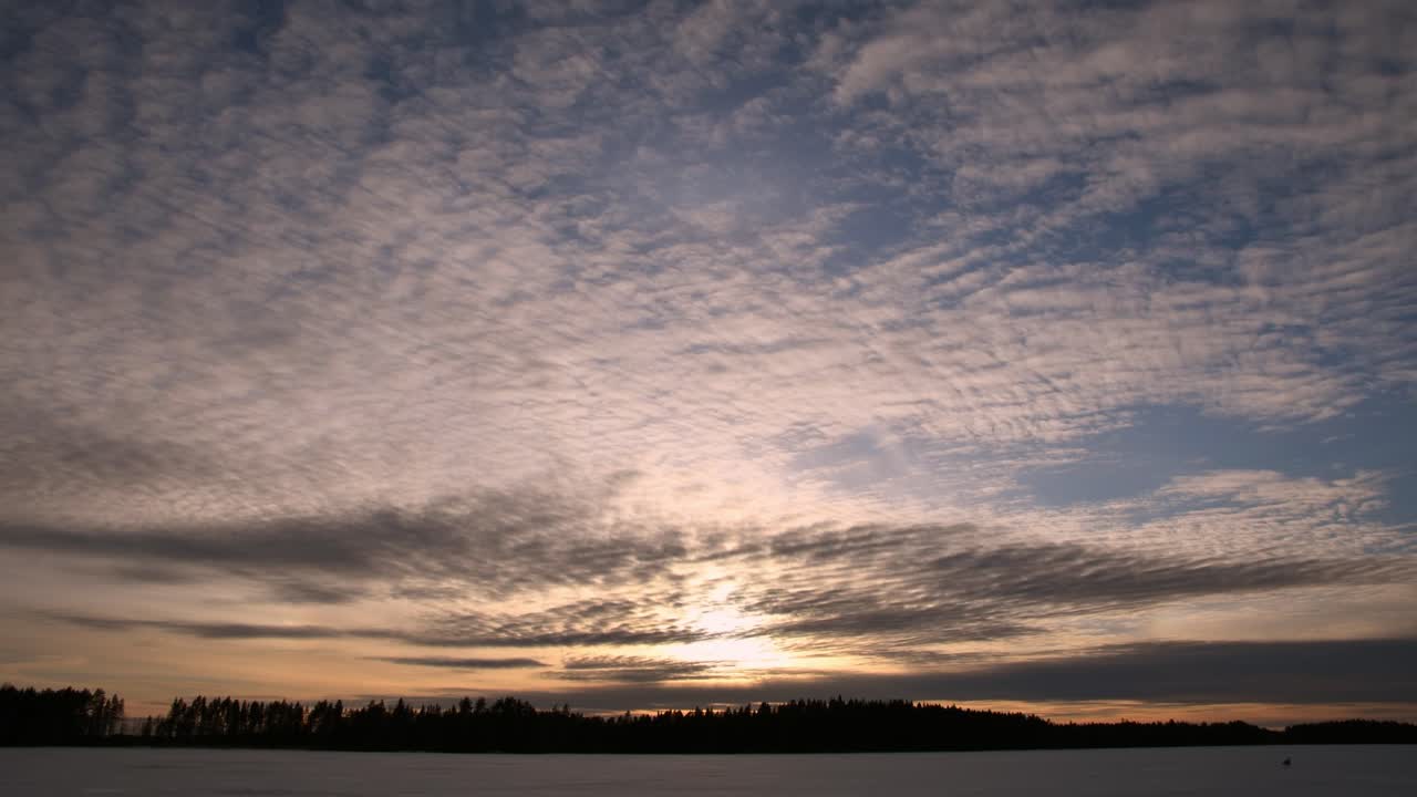 얼음 호수에서 일몰에 의해 서로 다른 방향으로 움직이는 구름의 시간 경과