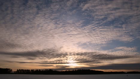 Zeitraffer-Von-Wolken,-Die-Sich-Bei-Sonnenuntergang-Auf-Einem-Eisigen-See-In-Verschiedene-Richtungen-Bewegen