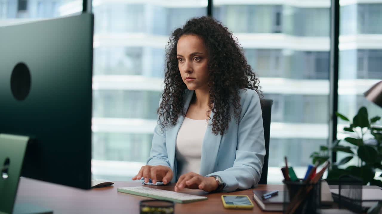 Focused girl office manager typing on keyboard sitting at desk close up.