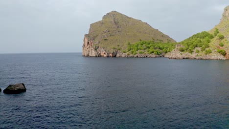 Revela-Una-Foto-De-Un-Enorme-Acantilado-Rocoso-De-La-Isla-En-El-Agua-De-Mar-Circundante,-Vista-Aérea