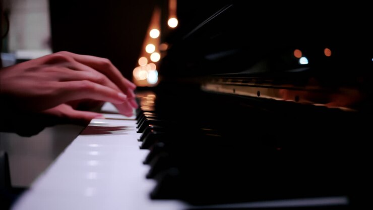 Close up of a woman's hands playing the piano with blurry lights on the background