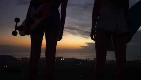 friends look out at the sunset sky panorama after a skateboarding session on the mountain