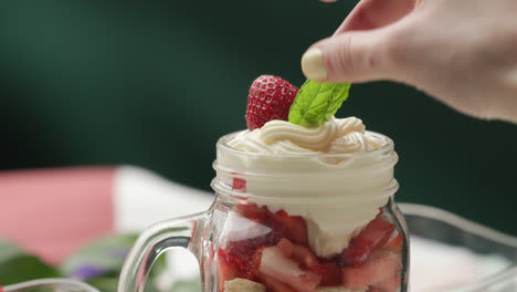 Garnishing-no-bake-strawberry-shortcake-trifle-in-jar-with-leaf-of-fresh-mint