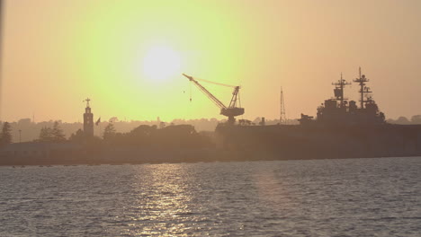 handheld, slider shot of naval ship docked in the san diego harbor sunset