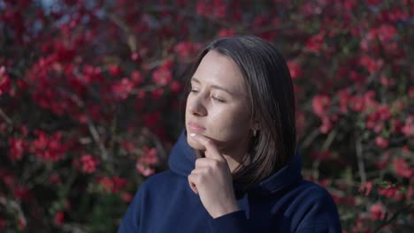 thoughtful female brunette stand near blossoming chinese quince shrub, czechia