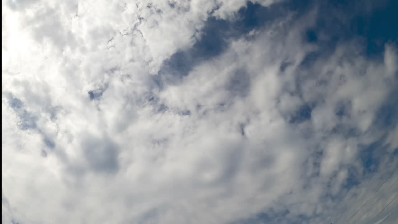 Stratus cloudscape covering the blue skies. Low angle view on the clouds gathering in the atmosphere. Timelapse.