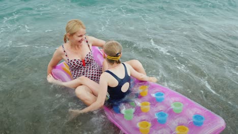 large waves of the sea carry an inflatable mattress with a mother and a child, a fun ride on the waves