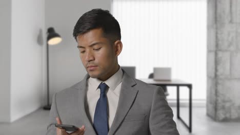 hombre de negocios serio en traje tomando llamadas por teléfono móvil en una oficina moderna de plan abierto