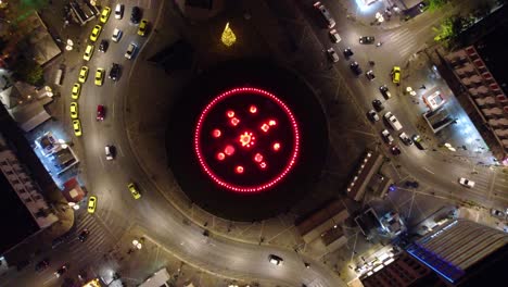 Vista-Aérea-Del-Tráfico-Alrededor-De-La-Fuente-De-Agua-En-La-Plaza-Omonoia-Por-La-Noche-En-Atenas,-Grecia