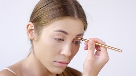 beautiful woman applying concealer around her eye