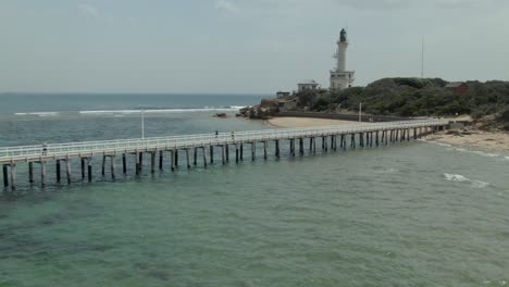 scenic view of a lighthouse and pier on a coastal beach
