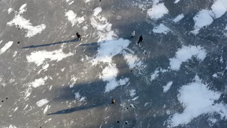 an aerial drone shot looking straight down on a group of friends playing ice hockey on a frozen lake - daytime