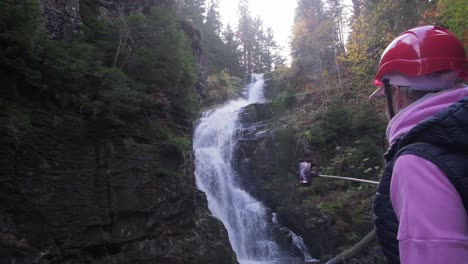 a person in a red helmet stands before a beautiful waterfall a determined person in a red helmet stands proudly before a stunning waterfall embodying adventure and resilience against natures beauty