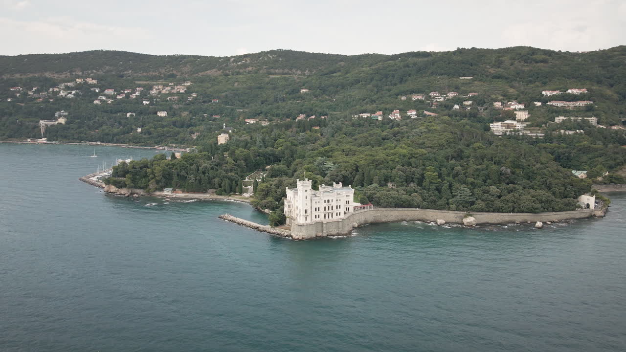 Valorizza la tua storia con un'orbita fluida di drone 4K UHD intorno al Castello di Miramare sul Golfo di Trieste, Italia, rivelando pareti rocciose e il mare color verde acqua per promozioni