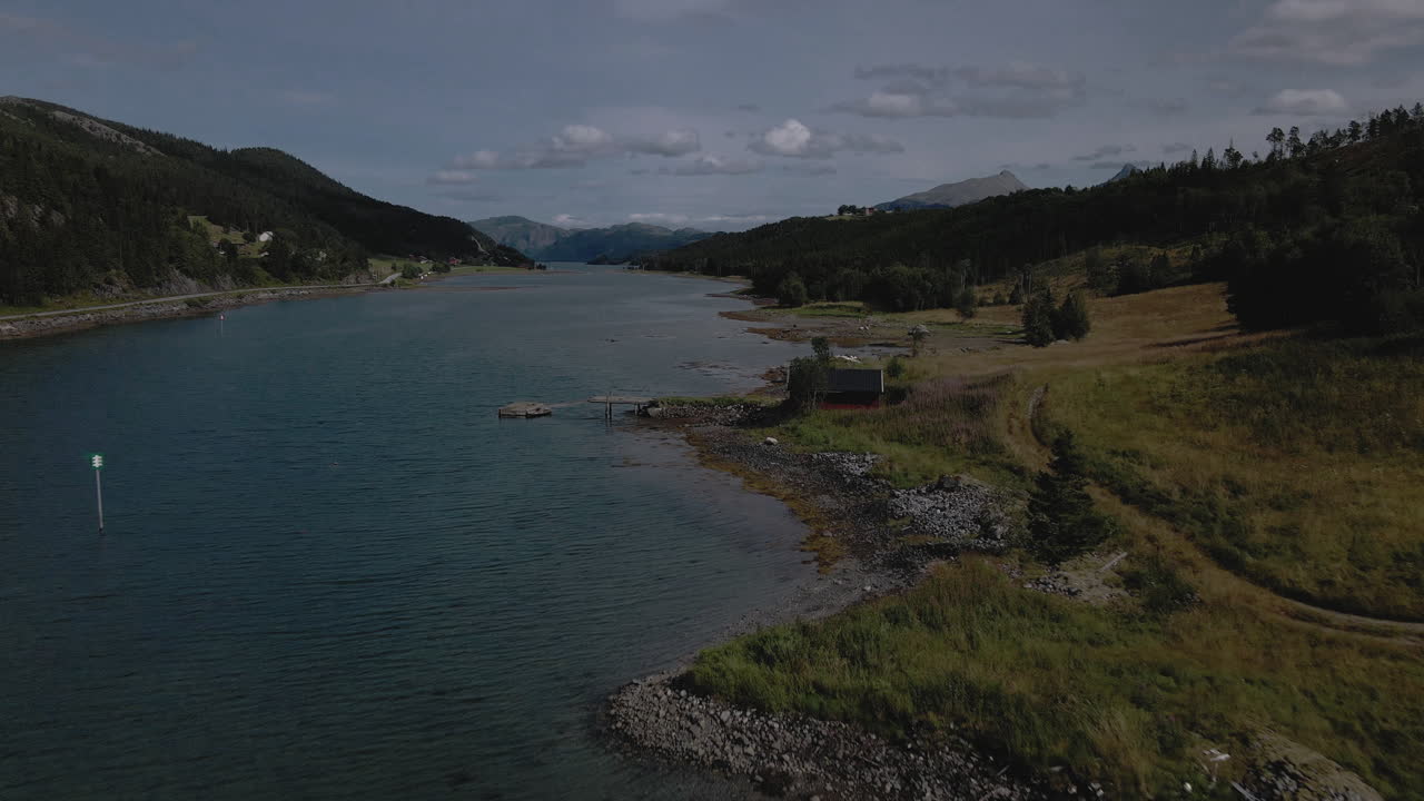 Flight Over Serene Ocean With Wooden Cottage By The Shore At Dusk In Nordland County, Norway. - Aerial Drone