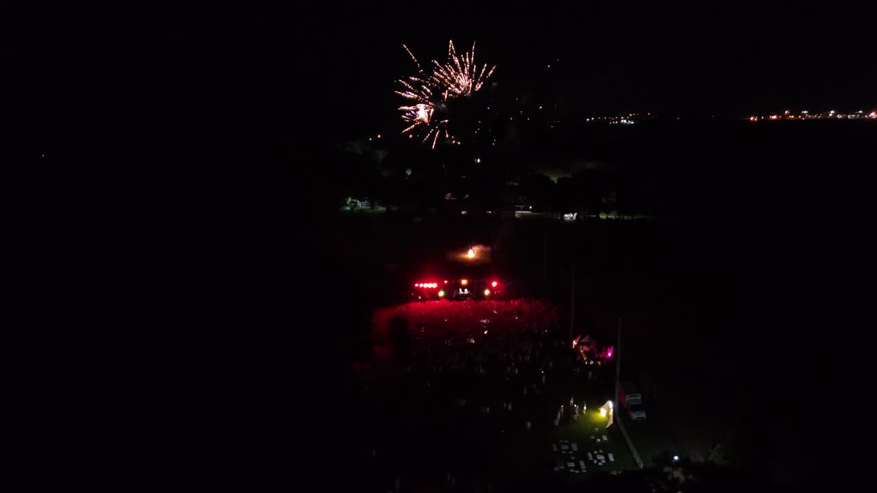 multitud de personas disfrutando de música y fuegos artificiales en la oscuridad