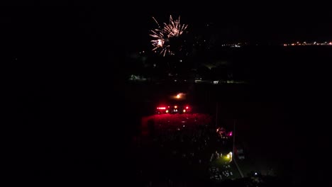 multitud de personas disfrutando de música y fuegos artificiales en la oscuridad