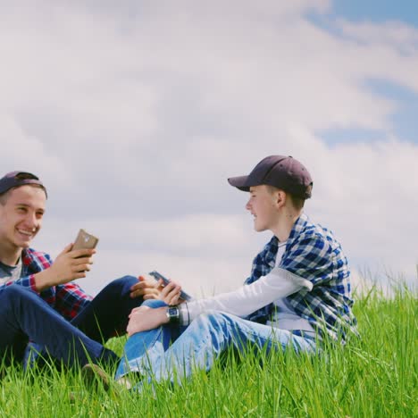Zwei-Junge-Teenager-Ruhen-Sich-In-Der-Natur-Aus-Und-Benutzen-Smartphones