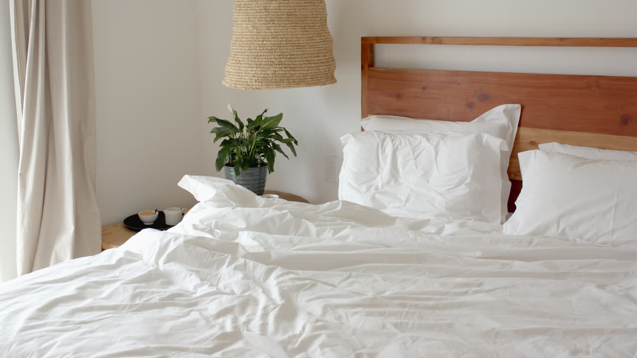 Cozy bedroom with unmade bed and morning light streaming through window, at home