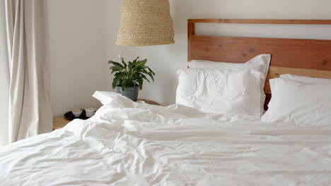 cozy bedroom with unmade bed and morning light streaming through window, at home