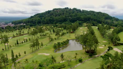 tropical vibrant golf course near foothills of tidar in magelang, indonesia, aerial view