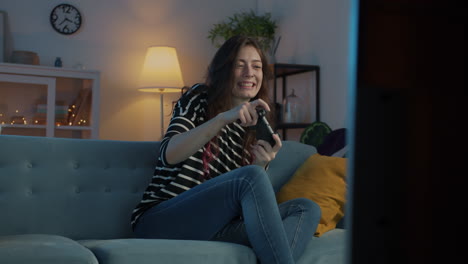 woman playing video game on the couch at night