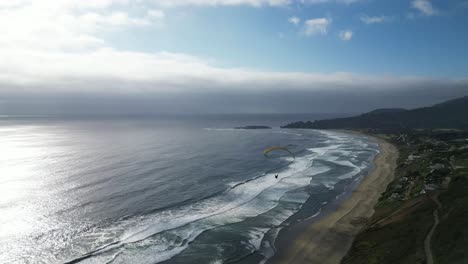 parapente amarillo en la costa del océano pacífico