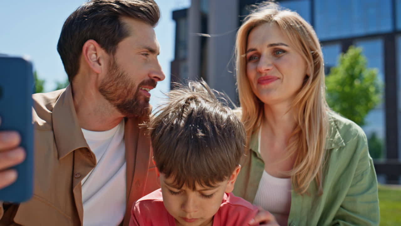 Happy family videocalling smartphone nature closeup. Mother father child talking