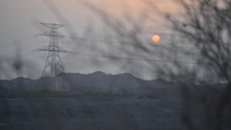 a serene middle eastern wadi at sunset, framed by leafless branches