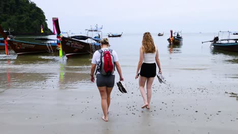 two people approach boats on ao nang beach