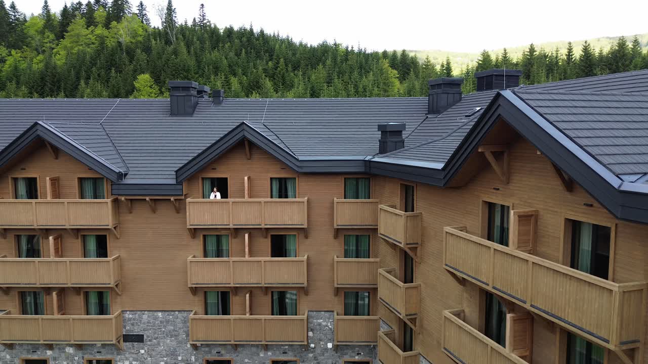 Luxury ski resort and mountain retreat wooden rustic building in Kolasin valley surrounded by lush pine forest in summer, Aerial closeup