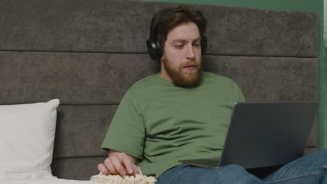 boy is watching videos on laptop while eating popcorns on the bed in bedroom 1