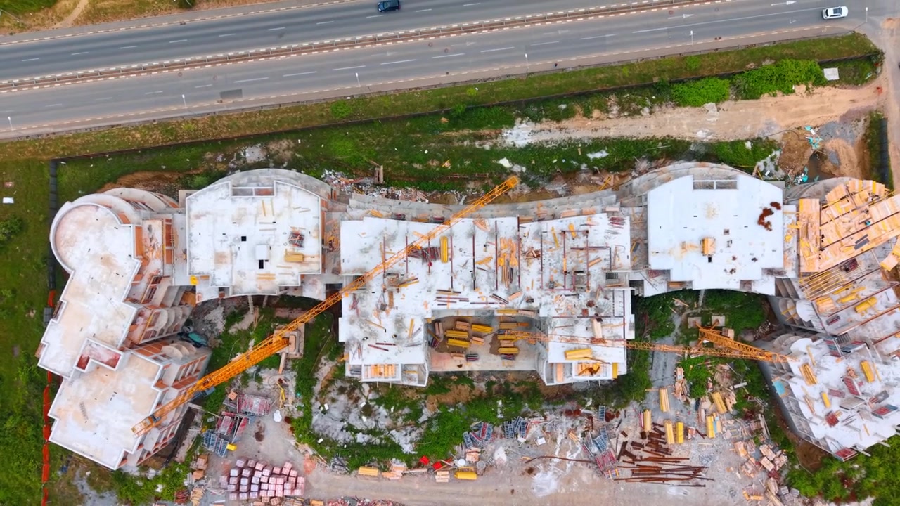 Directly above view of monolithic building construction and crane. Monolithic concrete building frame under construction with tower crane, viewed from a vertical bird's eye perspective.
