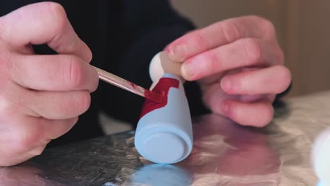 toma estática de un artista pintando muñecas caseras, cerca de artesanías hechas a mano