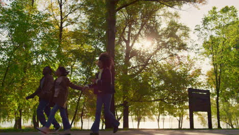 african american parents holding hands walking run green park walkway together.