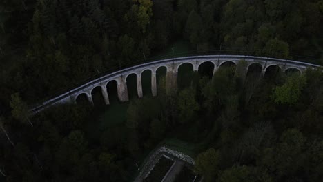 Electric-train-rail-bridge-alongside-a-vast-forested-mountainside-landscape