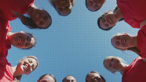 Portrait-Of-Womens-Soccer-Team-Joining-Hands-During-Motivational-Pep-Talk-Shot-From-Low-Angle-Below