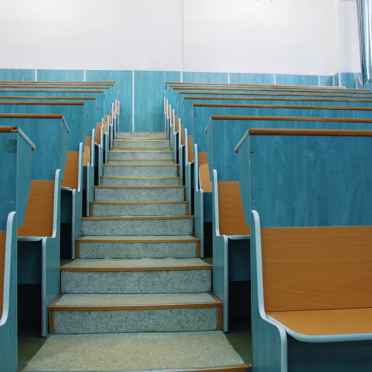 Empty auditorium. Stairs between two rows of desks in conference hall. Beautiful class for studying without students. Classroom in the university with wooden desks