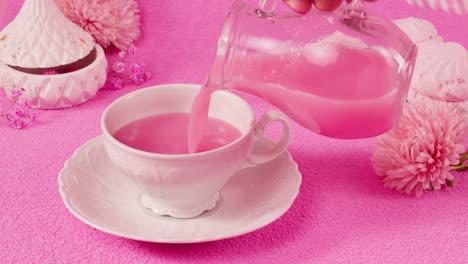 pink drink being poured into a tea cup