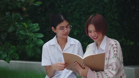 two students reading a book outdoors