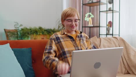 Young-woman-freelancer-sitting-on-couch-closing-laptop-pc-after-finishing-work-in-room-at-home